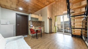 Una cocina compacta con comedor, un amplio ventanal corredera a un balcón y techo de madera.