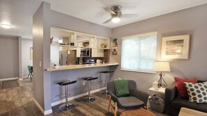 A compact living space with a kitchenette, a dining area, and a seating area with a sofa and chairs.