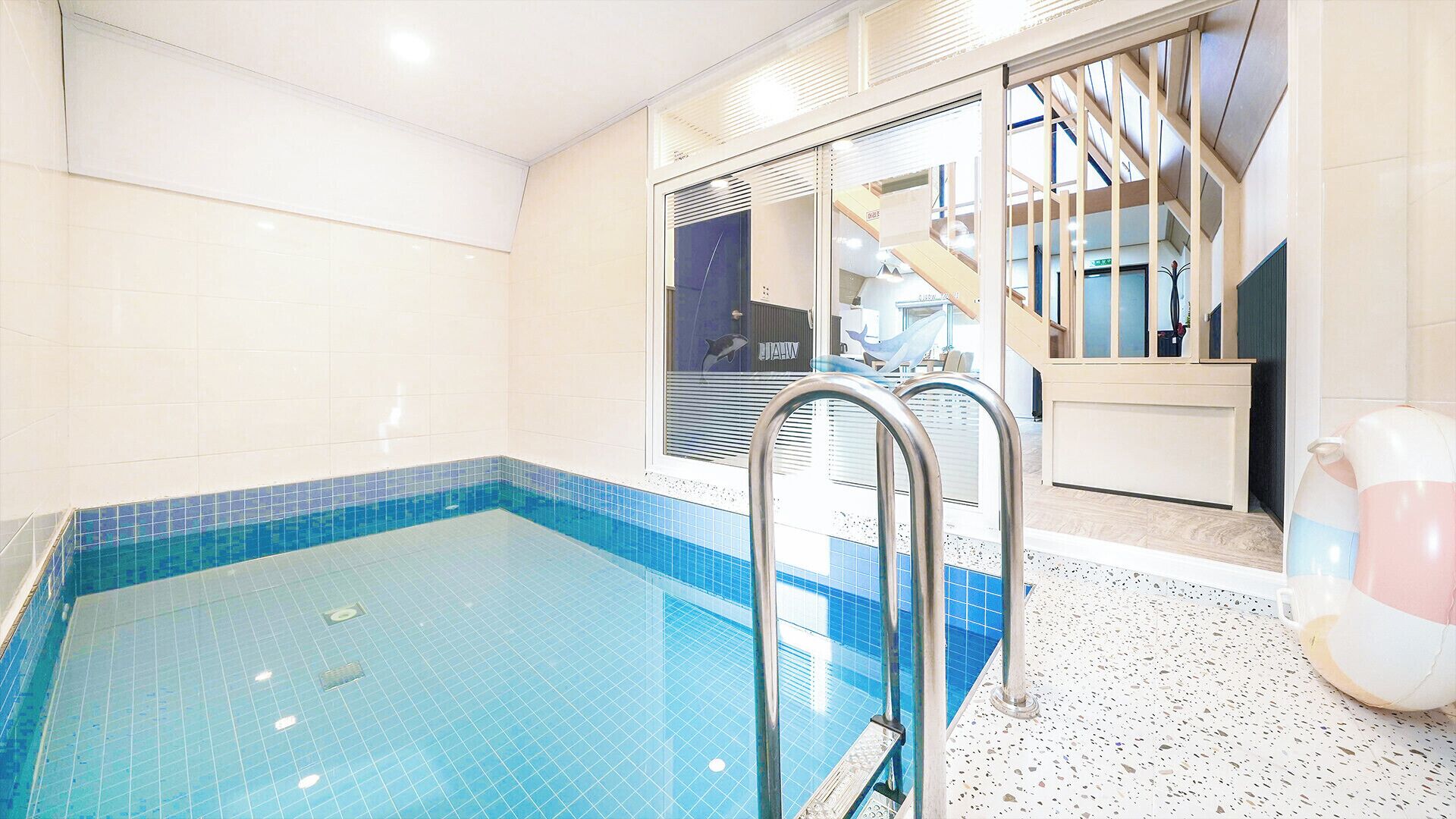 A swimming pool with a tiled edge, a metal ladder, and a view of a building with a dolphin sign.