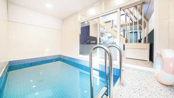 A swimming pool with a tiled edge, a metal ladder, and a view of a building with a dolphin sign.