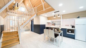 A modern kitchen with a central island, a dining area with chairs, and a staircase leading to an upper level. - Gapyeong The Paran Private Pool Villa (Gapyeong)