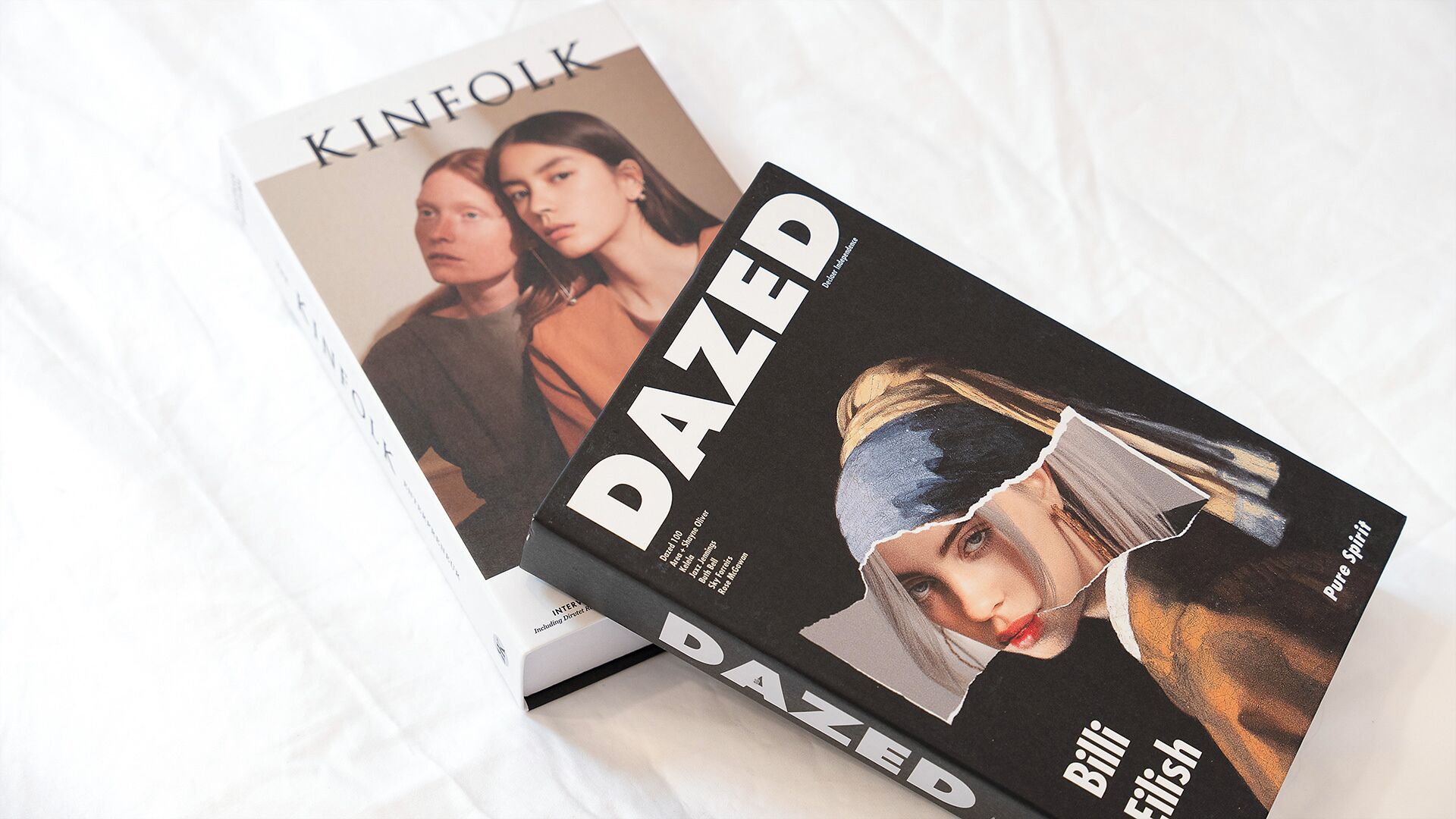 Two books titled 'KINFOLK' and 'DAZED' on a white surface.