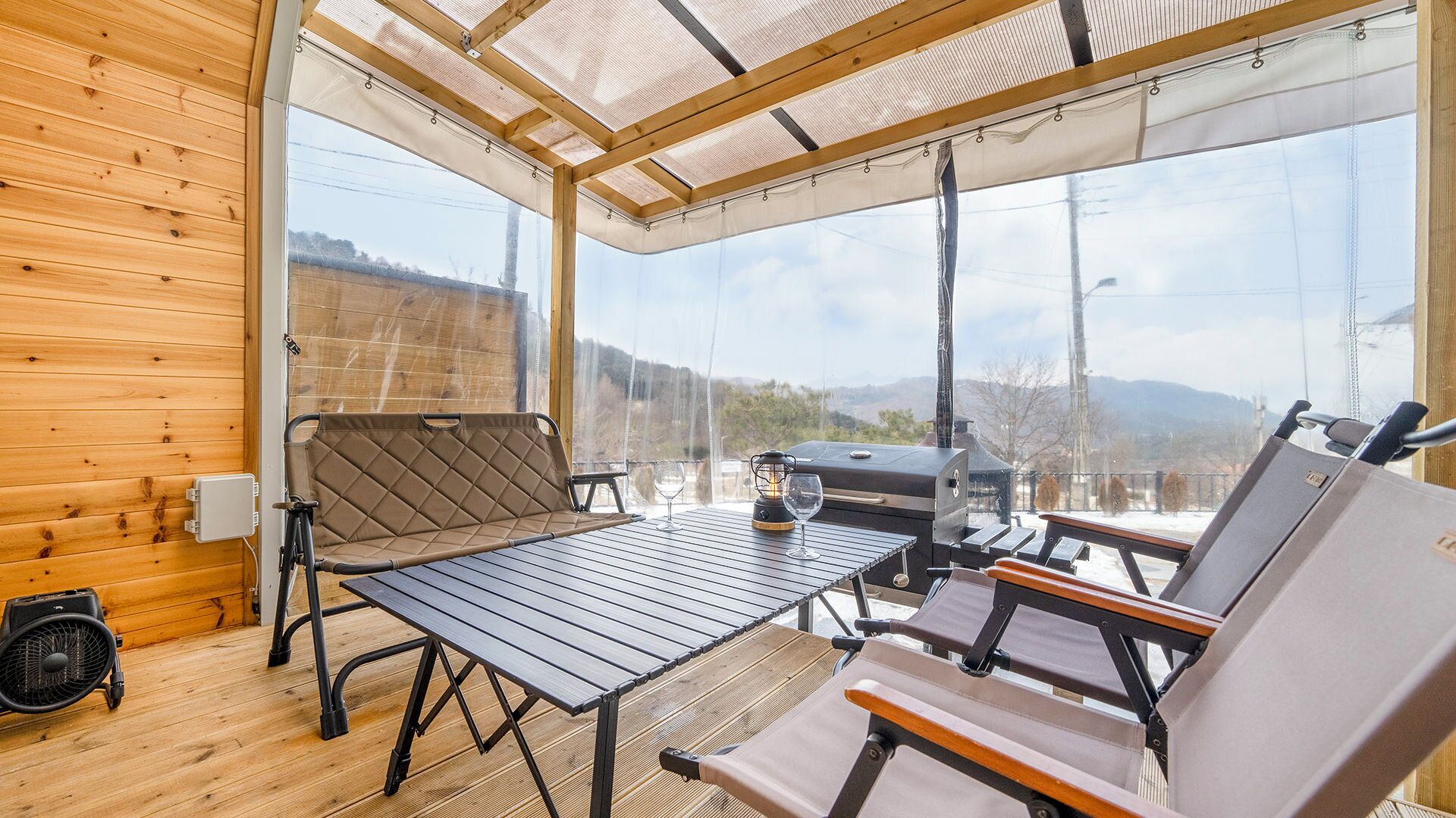 A wooden deck with a table and chairs, a grill, and a view of the mountains.