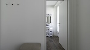 A narrow hallway leading to a bathroom with a vanity, mirror, and a window. - Italianway Comfort - Buenos Aires 65 E (Milan)