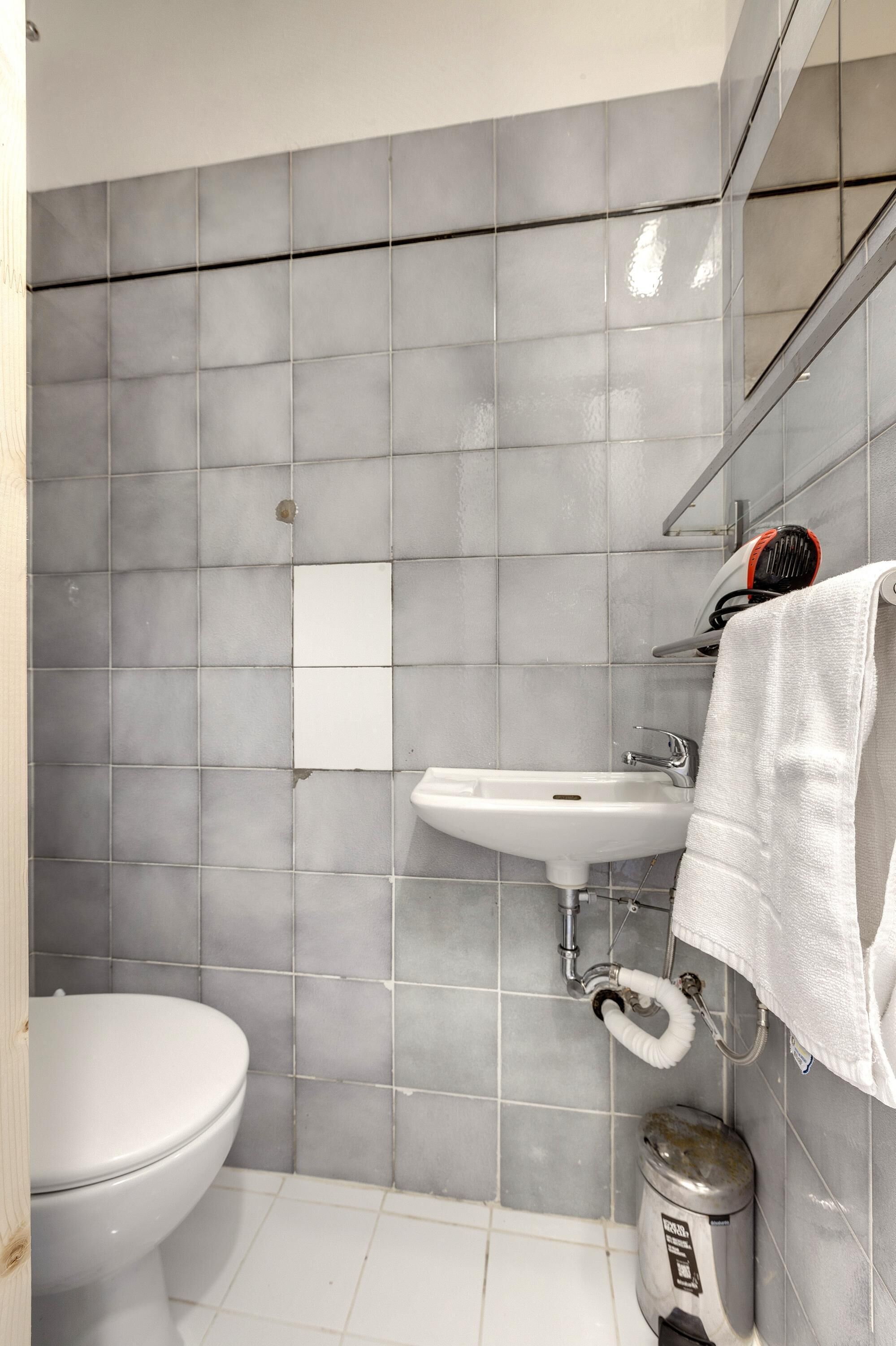 Une salle de bain équipée de toilettes, d’un lavabo et d’une poubelle.