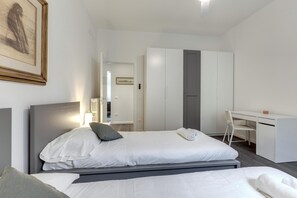 A modern hotel room with two beds, a desk, and a wardrobe. - Rossini 4 in Florence (Florence)