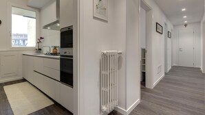 Et moderne køkken med hvide skabe, indbygget ovn og en radiator.