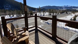 A wooden deck with Adirondack chairs overlooking a snowy landscape and mountains. - Frey Gulch 46 (Keystone)