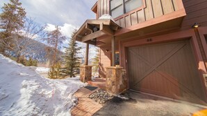 A wooden building with a stone entrance, a garage, and a snowy landscape with trees. - Frey Gulch 46 (Keystone)
