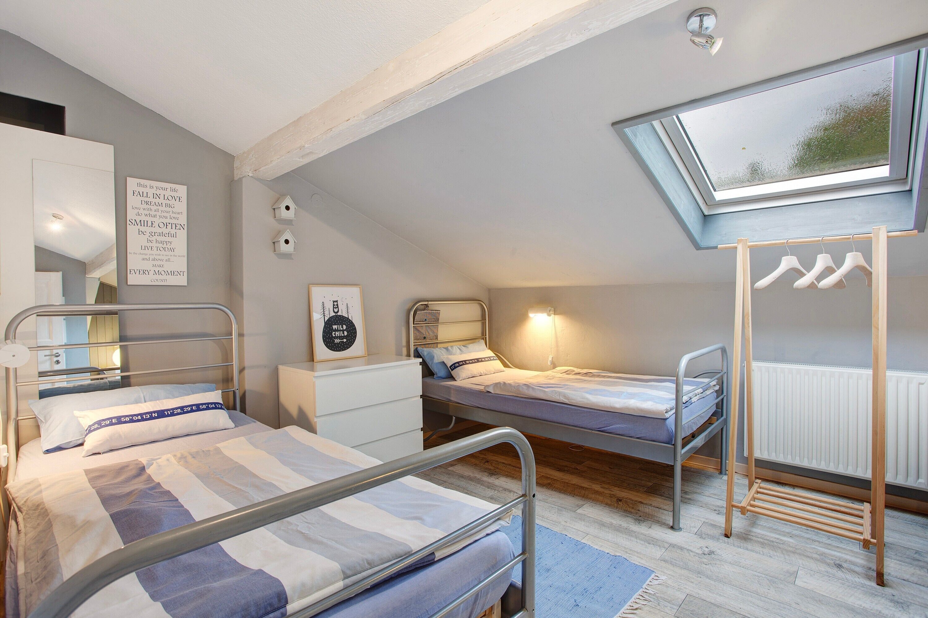 Ein Schlafzimmer mit zwei Etagenbetten aus Metall, einem Oberlicht, einem weißen Heizkörper und einem an der Wand befestigten Kleiderhaken.