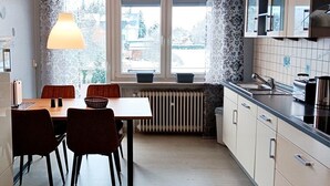 Et moderne køkken med et spisebord, stole, en radiator og et vindue med gardiner.
