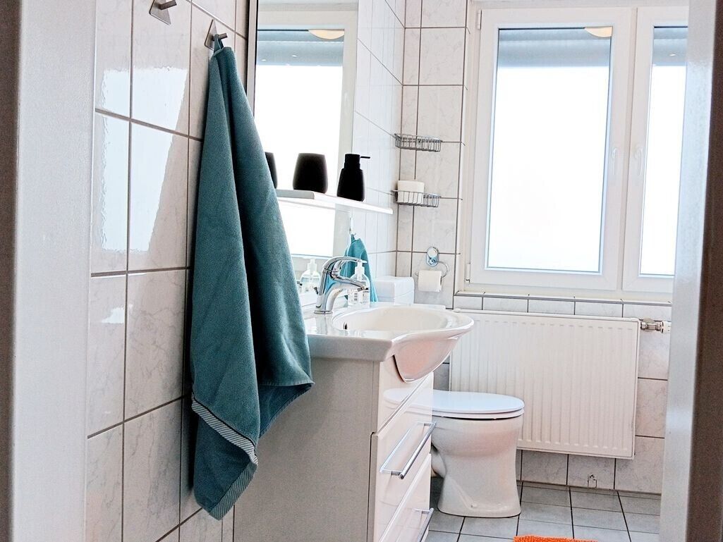Ein Badezimmer mit einem weißen Waschbecken, einer Toilette und einem Fenster.
