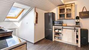 Een keuken met dakraam, een koelkast, een houten kast en een koffieapparaat.