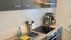 Eine moderne Küche mit Spüle aus Edelstahl, einer Kaffeemaschine und einem Einbauofen.