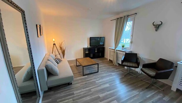 Ein Wohnzimmer mit einer Couch, einem Couchtisch, einem Fernseher, einem Sessel und einem dekorativen Bullenkopf an der Wand.
