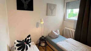 Ein Schlafzimmer mit zwei Betten, einem Heizkörper, einem Fenster mit Vorhängen und Wandbildern.