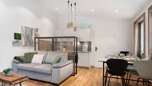 Una sala de estar moderna con un sofá gris, una mesa de centro de madera y un comedor con una mesa dispuesta para dos.