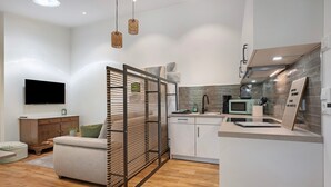 Una cocina moderna con microondas integrado, hervidor de agua y un refrigerador pequeño.