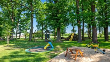 Un parque infantil con tobogán, columpios y zona de arena.