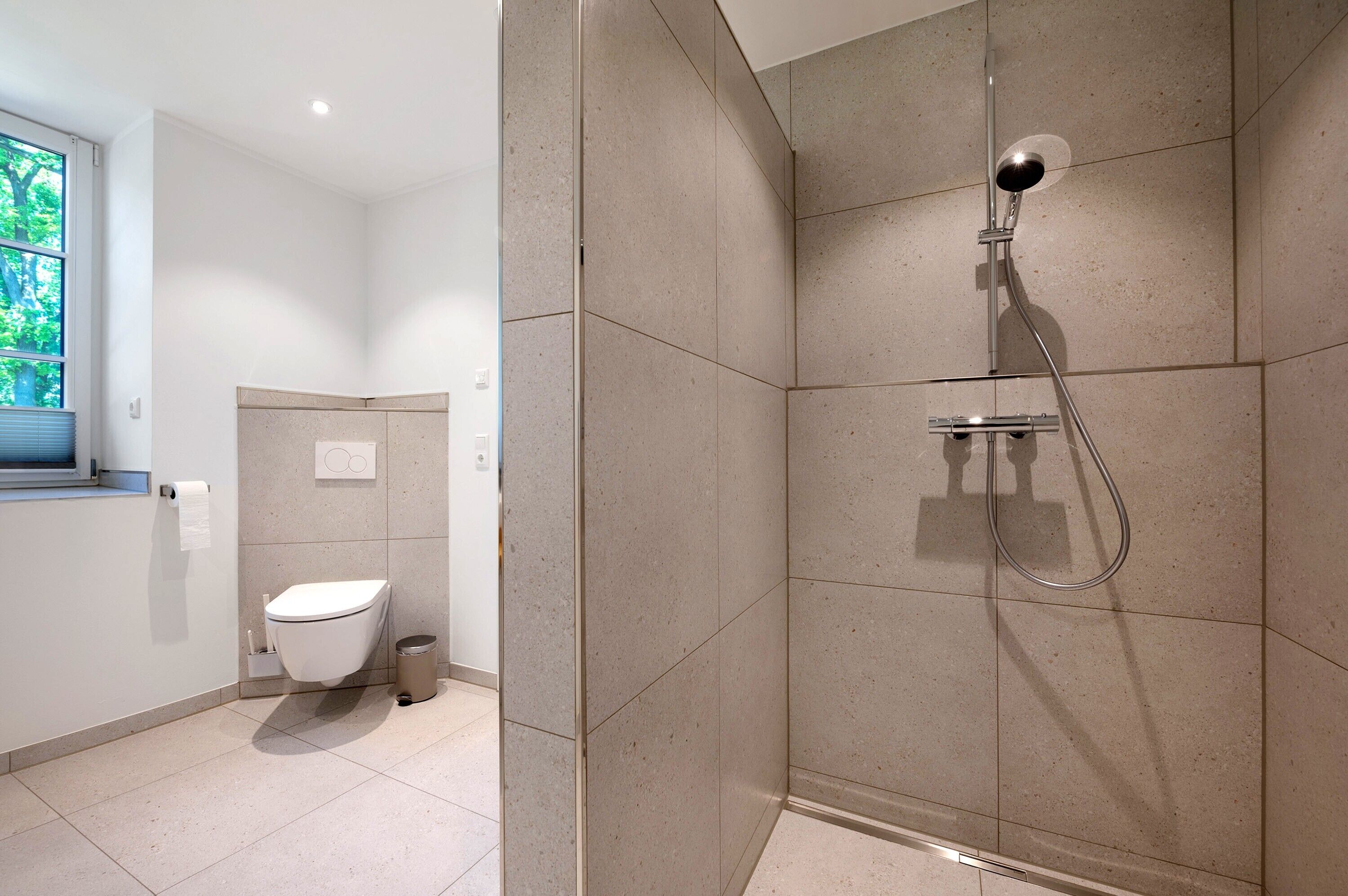 Une salle de bain moderne équipée d’une douche, de toilettes et d’une fenêtre.