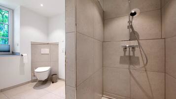 Une salle de bain moderne équipée d’une douche, de toilettes et d’une fenêtre.