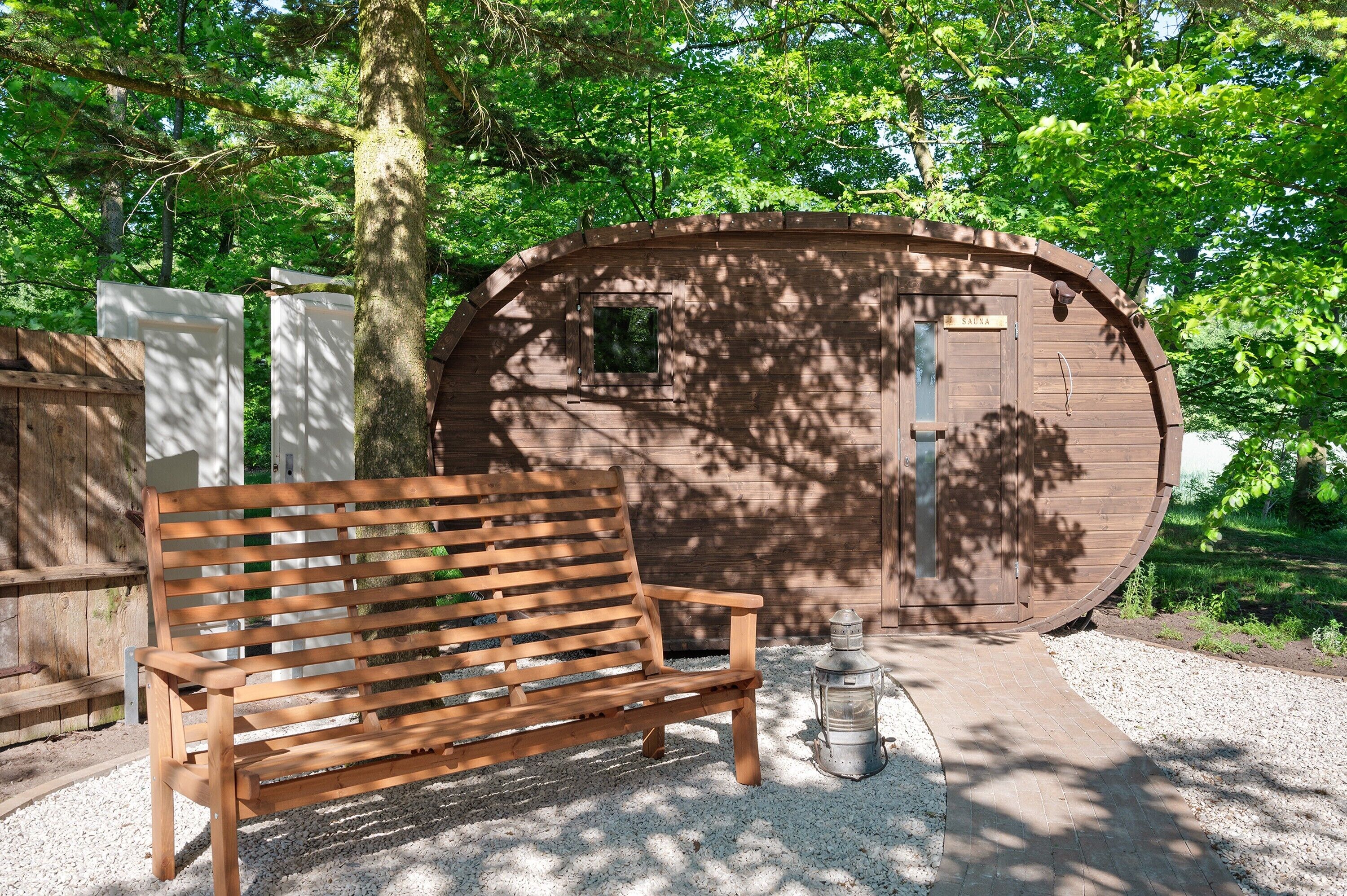 Un banc en bois, une lanterne et une structure en bois dotée d’une porte et d’une fenêtre.