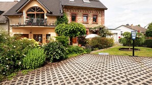 Une maison à deux étages avec un balcon, un jardin et une allée pavée.