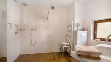A modern bathroom with a shower, a toilet, a sink, and a mirror.