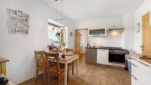 Une cuisine compacte avec des meubles blancs, une table à manger en bois et un petit îlot central.