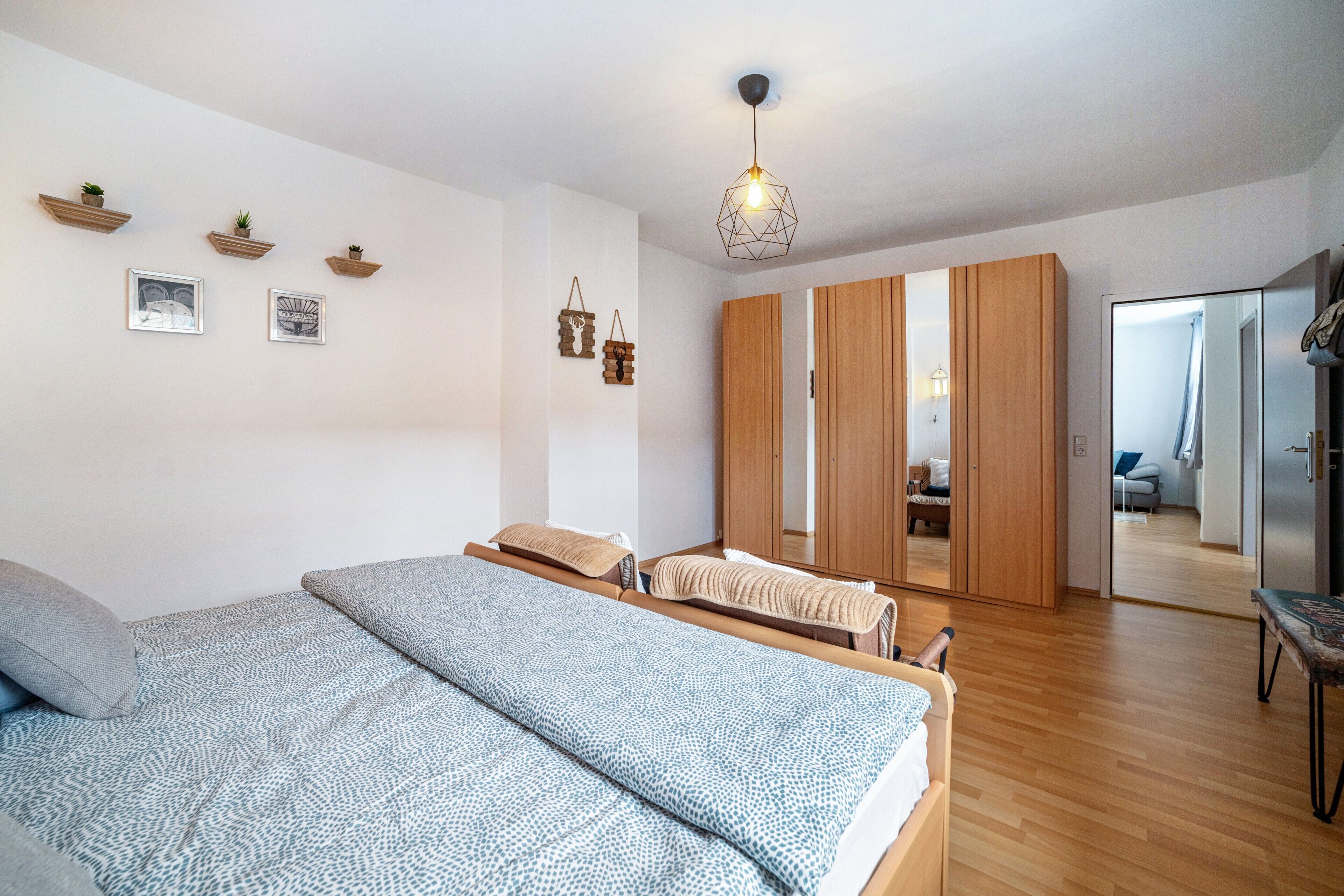Une chambre à coucher comprenant un lit, une armoire, un miroir et un luminaire suspendu.