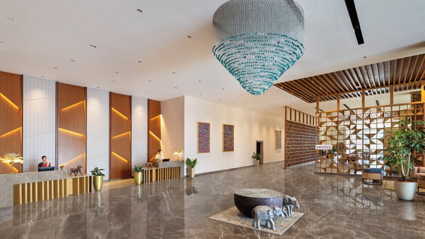 A modern lobby with a reception desk, a large chandelier, and a seating area with a decorative elephant sculpture. - Welcomhotel By ITC Hotels Belagavi (Belagavi)