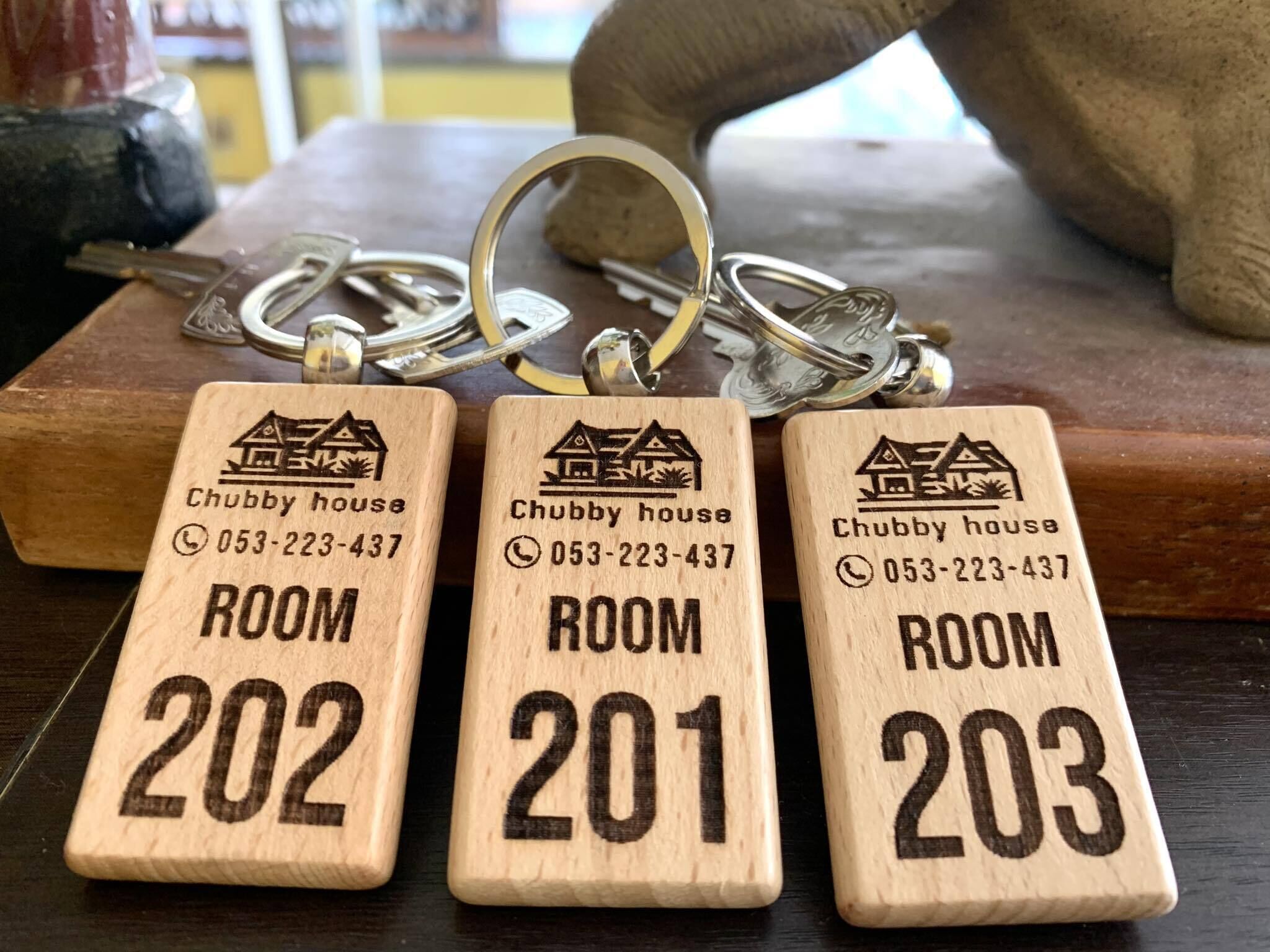 Three wooden key tags with room numbers and a phone number for Chubby House.