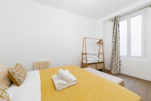 Une chambre d’hôtel avec un lit, une échelle en bois, une fenêtre avec des rideaux et un radiateur.