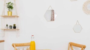 Ein runder Holztisch mit vier Stühlen, einer Orangensaftflasche und einem Teller mit Croissants.