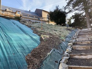 Stroll through the beautifully maintained garden, featuring a series of steps leading up to a lush raised bed.