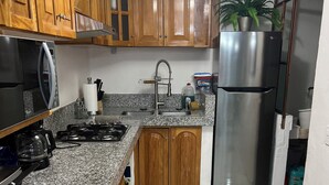 Una cocina con armarios de madera, encimeras de granito, un refrigerador de acero inoxidable y una estufa a gas.
