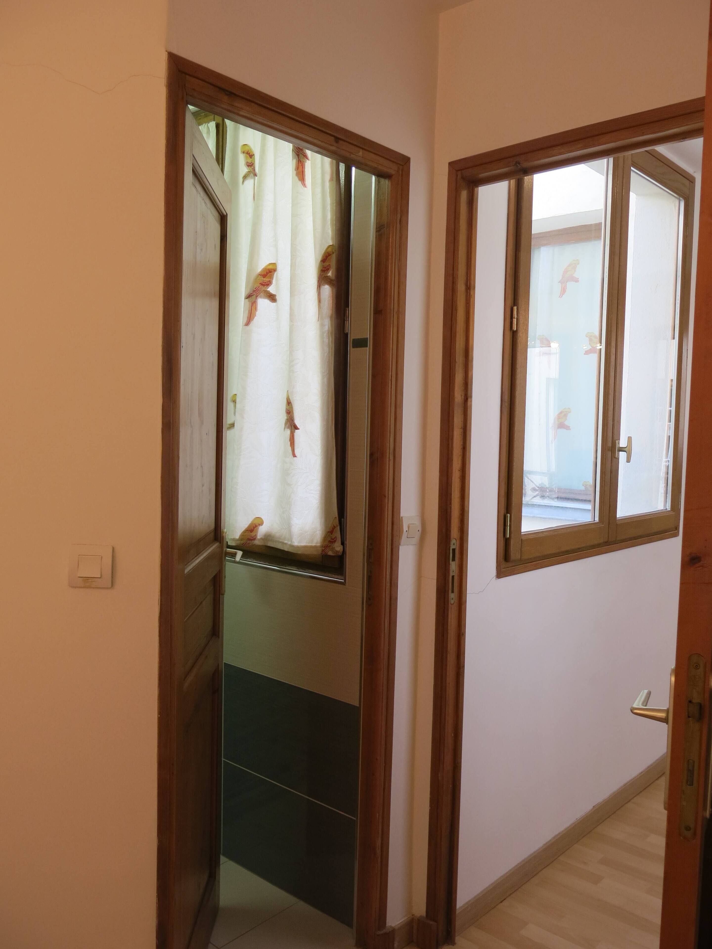 A hallway with a wooden door and a window with a curtain.