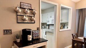 Una cocina con gabinetes blancos, un microondas y una cafetera sobre la encimera.