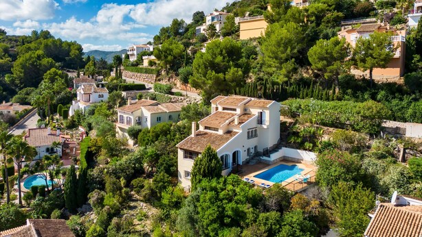A hillside residential area with houses, a swimming pool, and lush greenery.