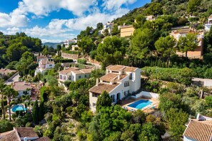 Una zona residencial en una ladera con casas, piscina y abundante vegetación.