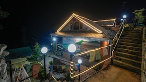 A house with a sloped roof, a staircase leading up to it, and a mural on the side. - Dharamshala Village Resort (Dharamshala)