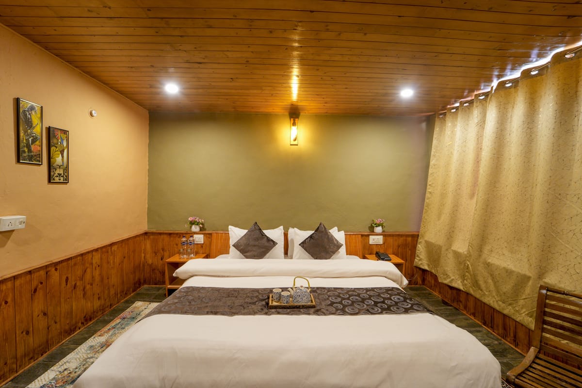 Quarto bem arrumado com teto de madeira, cama com roupa de cama branca, duas mesas de cabeceira com abajures e um tabuleiro decorativo na cama.