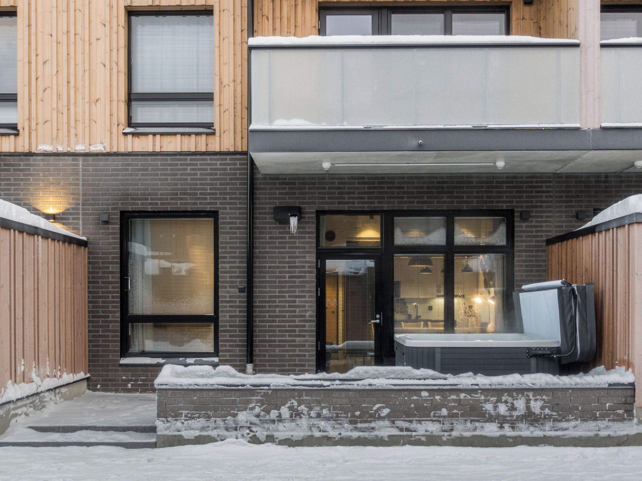 Ein zweistöckiges Gebäude mit Ziegelverkleidung, Holzfassade und Glastür.