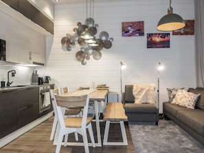 Et moderne køkken med hvide skabe, et spisebord med stole, en sofa og en gulvlampe.