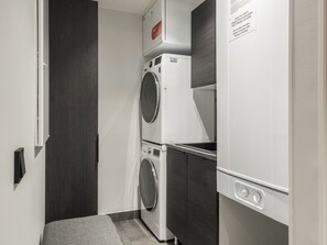A laundry room with a washing machine and dryer, a small countertop, and a door with a sign.