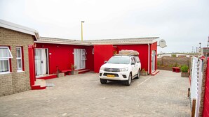 Een witte SUV staat op een oprit, met een rood gebouw op de achtergrond.