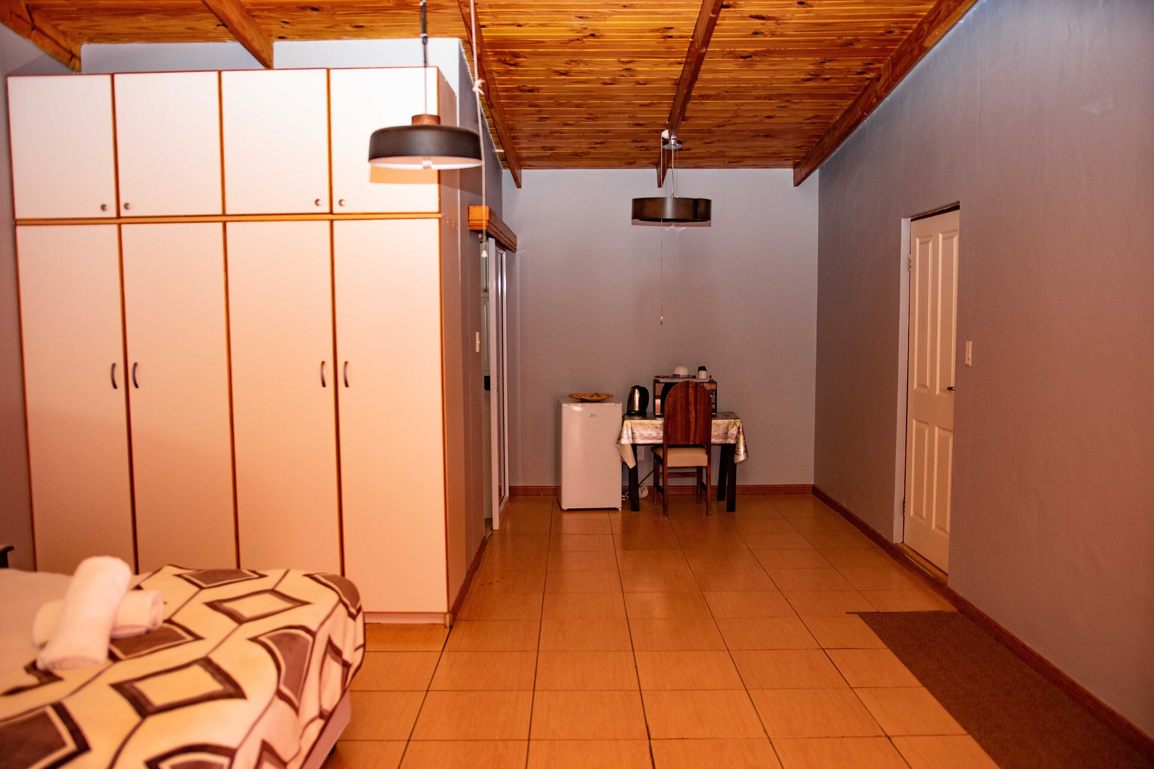 Un dormitorio con cama, armario y una pequeña zona de kitchenette.
