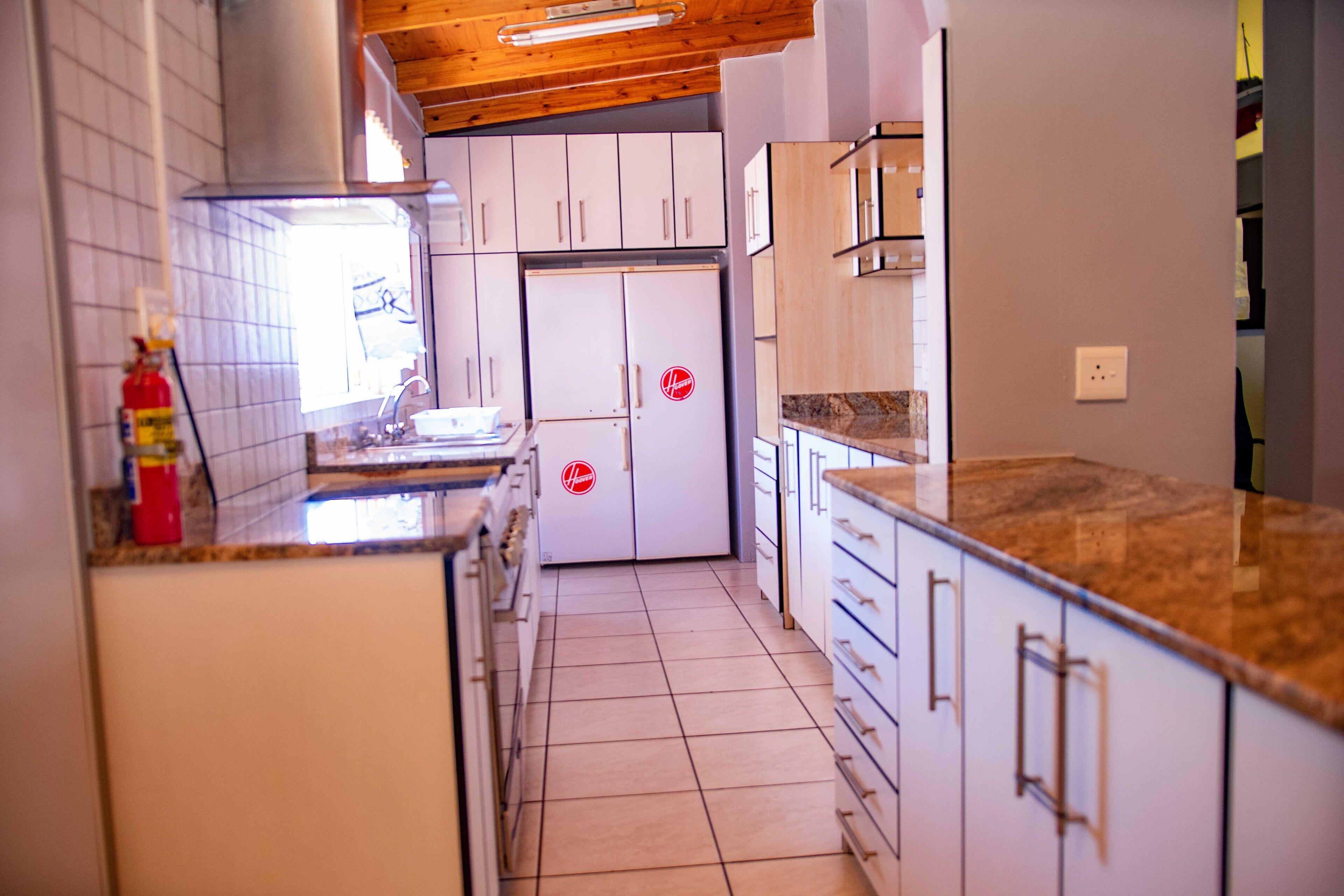A kitchen with white cabinets, a marble countertop, and a tiled floor.