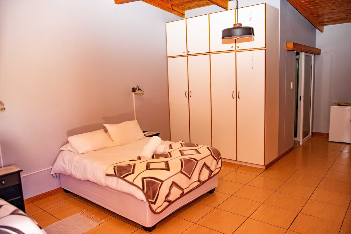 Un dormitorio con cama, armario, mesita de noche y lámpara.