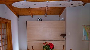 Een eetruimte met een houten tafel en stoelen, een plant in pot en een kaart aan de muur.